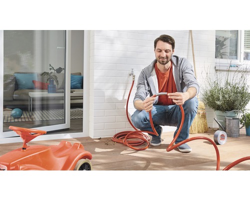 Man ansluter en trädgårdsslang till en utomhuskran