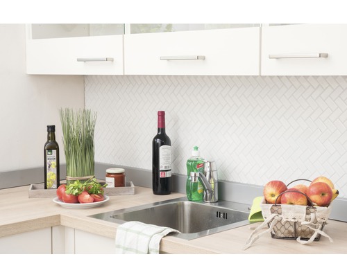 Köksscen med diskho, blandare och diverse köksredskap på bänkskivan.