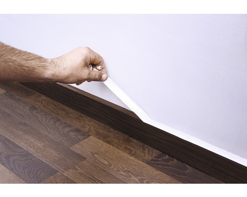 Montering av en golvlist på en vägg ovanför ett trägolv