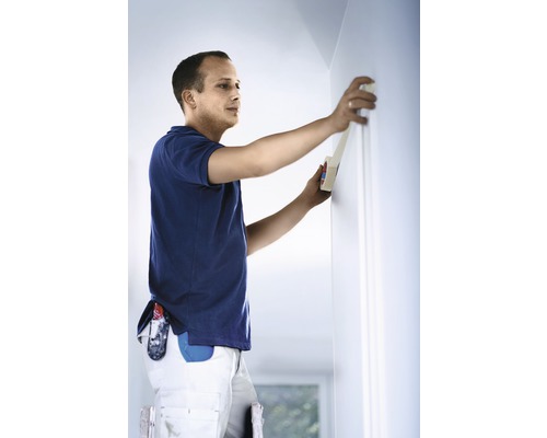 Hantverkare tejpar en vägg med målartejp.