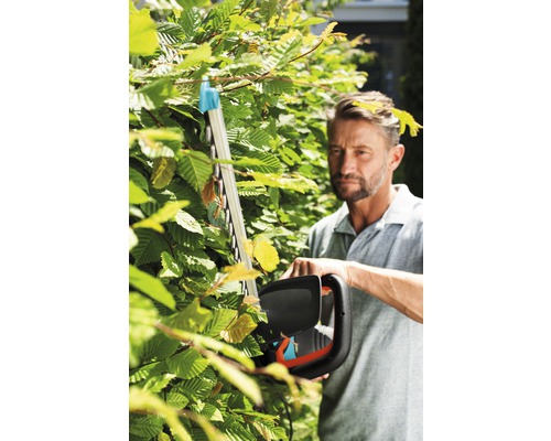 Man klipper häck med en häcksax