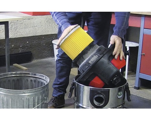 Person som kastar filtret från en dammsugare i en papperskorg