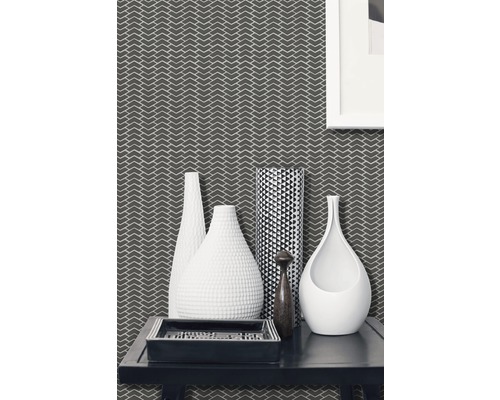 Dekorativt vardagsrum med mönstrad tapet, olika vaser och en rektangulär bricka på ett bord.