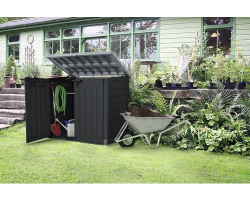 Trädgårdsscen med en verktygslåda, öppen, med trädgårdsredskap och en skottkärra fylld med jord.