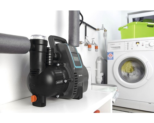 Trädgårdspump i tvättstugan bredvid en tvättmaskin och rör