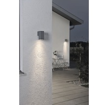 Belyst husfasad med modern vägglampa.