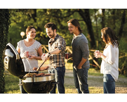 Folk grillar utomhus med en kolgrill.