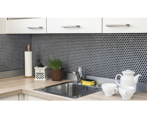 Köksscen med diskho, kran, mosaikplattor och köksredskap på bänkskivan.