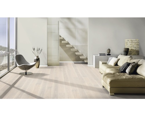 Ljust vardagsrum med trägolv, soffa, fåtölj och trappa