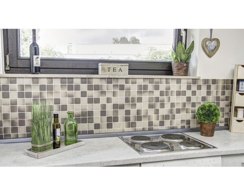 Köksscen med mosaikplattor, kokplatta och dekorativa element.