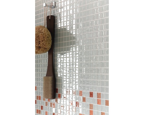 Detaljbild av en vägg med mosaikplattor, en badsvamp och en borste