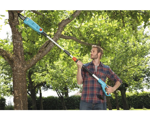 Man använder en lång räckvidd motorsåg för att trimma ett träd.