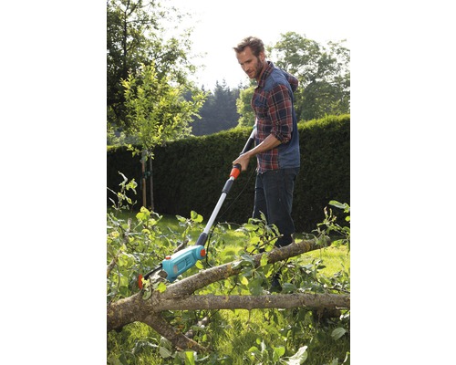 Man använder en grensåg för att såga grenar i trädgården.