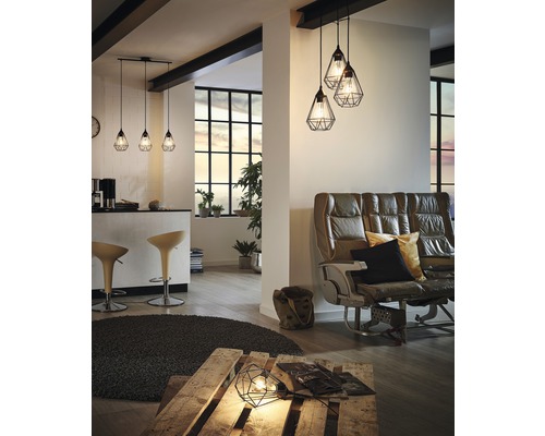 Vardagsrum med sittplatser, barbord och flera hänglampor med trådskärm