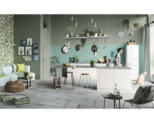 Kök med vita köksskåp, mosaikplattor och trägolv i ett öppet vardagsrum med dekorationer