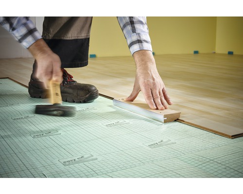 Lägga laminat med hammare och slagkloss på stegljudsisolering.