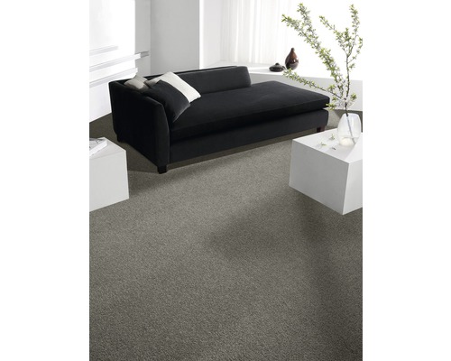 Ljust rum med grå heltäckningsmatta, svart soffa och vita sidobord