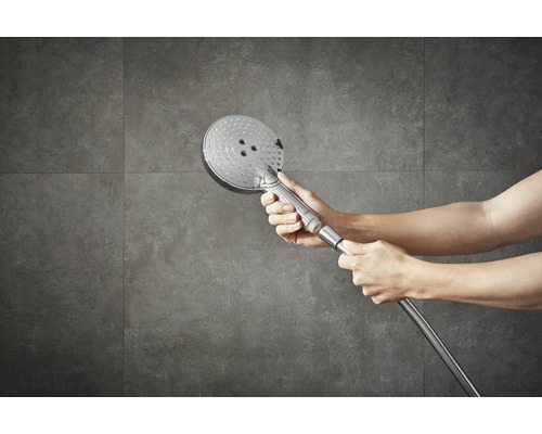 Handdusch med duschslang framför kakelvägg