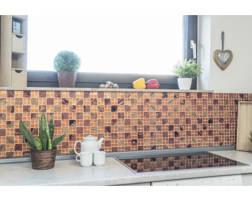 Köksscen med mosaikplattor, växter och köksredskap på bänkskivan.