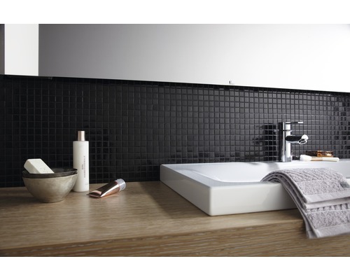 Modernt badrum med tvättställsskål, blandare, handduk och mosaikplattor