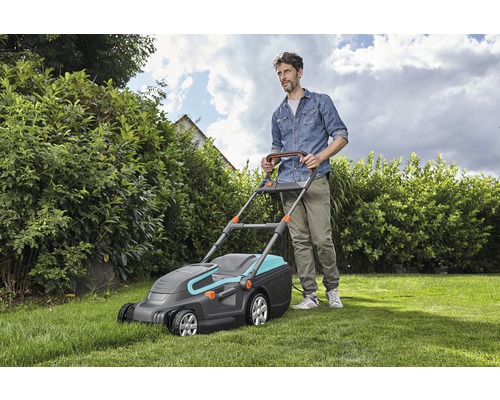 Man klipper gräs med en Gardena gräsklippare i trädgården.