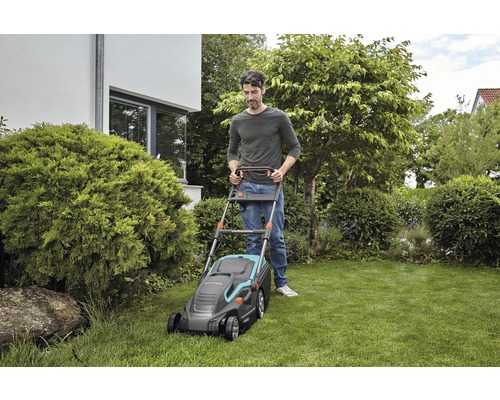 En man använder en Gardena gräsklippare i en trädgård.