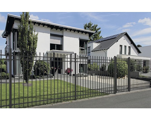 Ett smidesjärnsstaket omger ett modernt bostadshus.