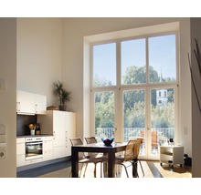 Ljust vardagsrum med pentry, matbord och stort fönster med utsikt över grönområden