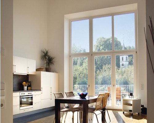 Ljust vardagsrum med pentry, matbord och stort fönster med utsikt över grönområden