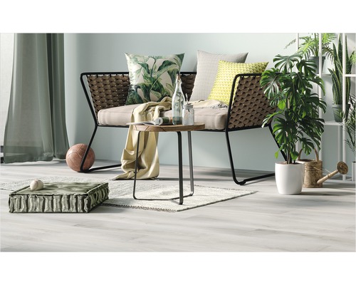 Vardagsrumsscen med soffa, bord, kuddar och växter för en mysig atmosfär.