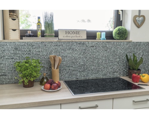 Köksscen med mosaikvägg, spishäll och köksredskap på en arbetsbänk.