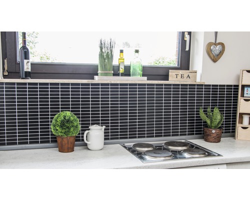 Köksscen med svarta plattor, spishäll, fönster och dekorationer.