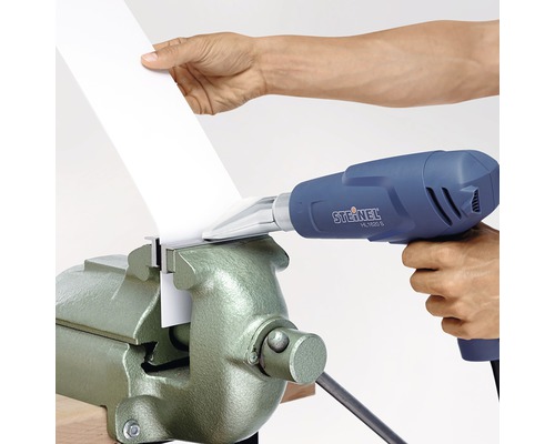 En värmepistol används för att bearbeta ett arbetsstycke i ett skruvstäd.