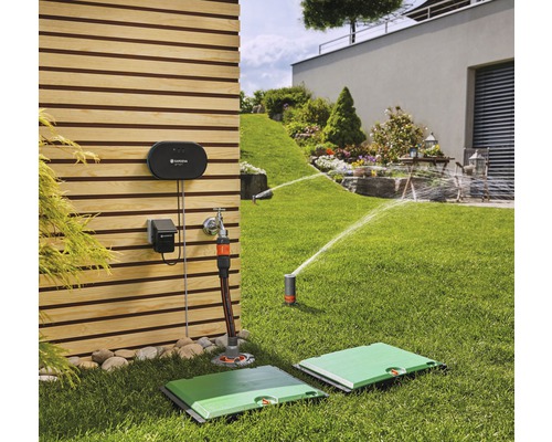 Scen med en trädgård med ett bevattningssystem, inklusive pop-up-spridare och kontrollutrustning på en trävägg.