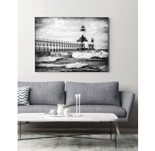 Fototryck på duk av en svartvit bild av en fyr i slutet av en pir ovanför havet