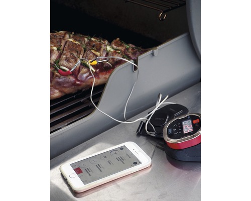 Grilltermometer i drift med kött på grillen och smartphone-app för temperaturövervakning