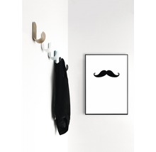 Vägghylla med jacka och inramad mustaschbild på väggen