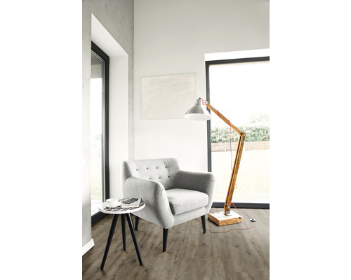 Ljust vardagsrum med fåtölj, golvlampa och sidobord på golv