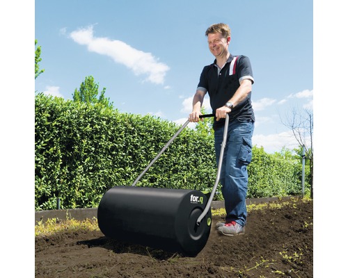 En man använder en trädgårdsvält från for.q i trädgården.