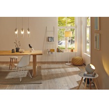 Ljust vardagsrum med matbord, stolar, stegregal, golvlampa och hänglampor för en vänlig atmosfär.