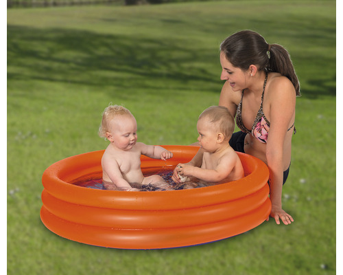 Uppblåsbar barnpool med två barn och en kvinna i trädgården.