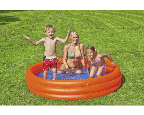 Familj med barn i plaskdamm i trädgården