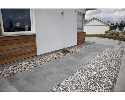 Exteriör av ett hus med gatstenar, grus och stenar.