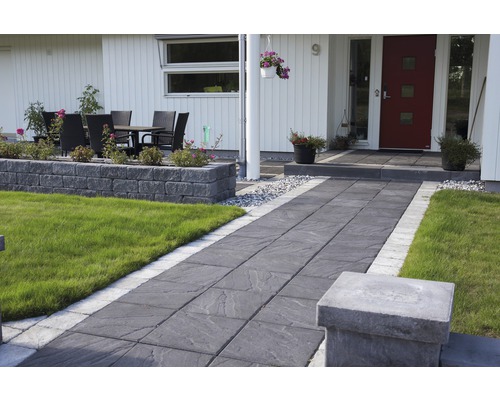 Trädgårdsgång med stenläggning och gräsmattor framför ett hus