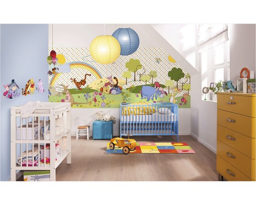 Ett barnrum med en Nalle Puh-tapet, en blå barnsäng, en skötbyrå och en gul byrå.