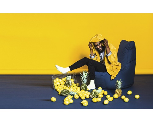 Man sitter i fåtölj med citron och ananas