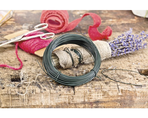 Rulle grön blomstertråd bredvid lavendel och presentband på ett träbord