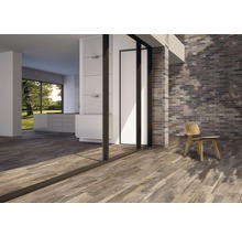 Ljust rum med trägolv, tegelvägg och stol.