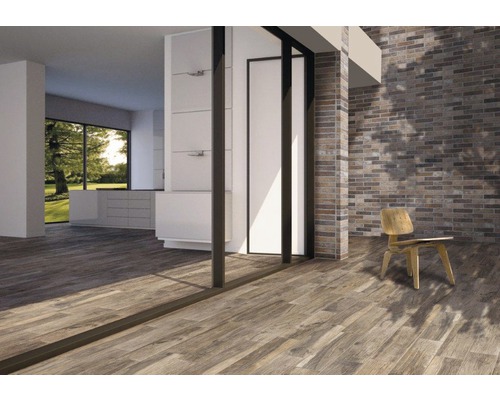 Ljust rum med trägolv, tegelvägg och stol.