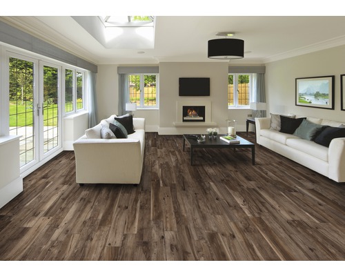 Ljust vardagsrum med brunt trägolv, vita soffor och öppen spis.